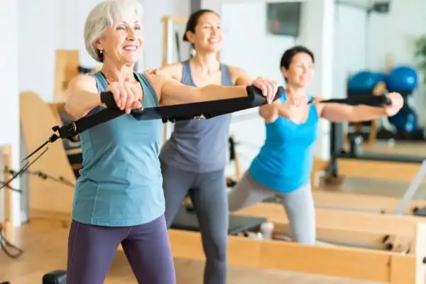 Toning Arms After 60: Empowering Womens Fitness Through Effective Weight Training 2 older woman doing weight training Borehamwood and resistance in the gym to tone upper arms