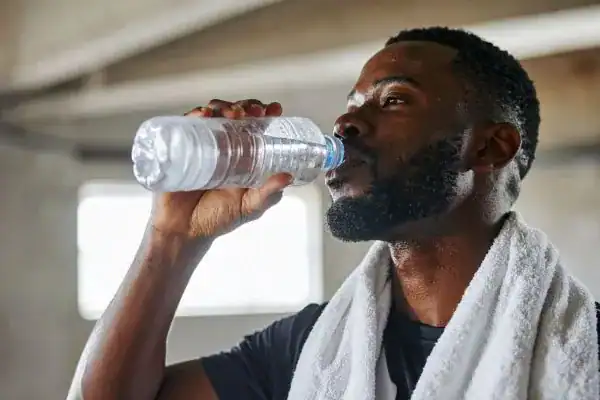Image of man drinking water to improve hydration Borehamwood after work out.